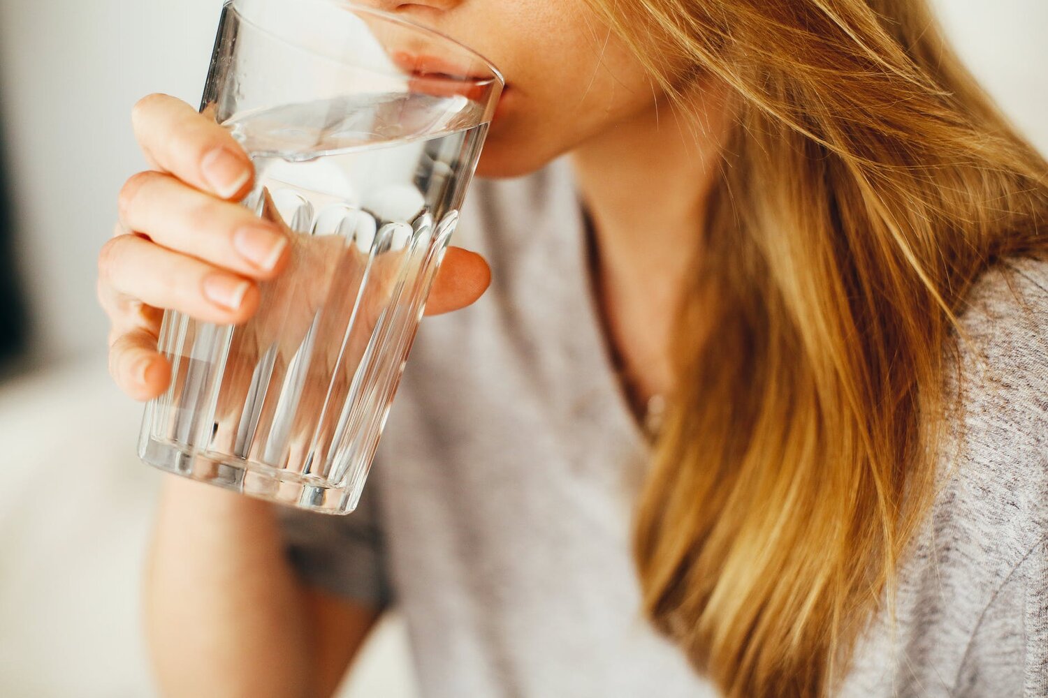 A clear glass of water on a wooden table beside fruit
